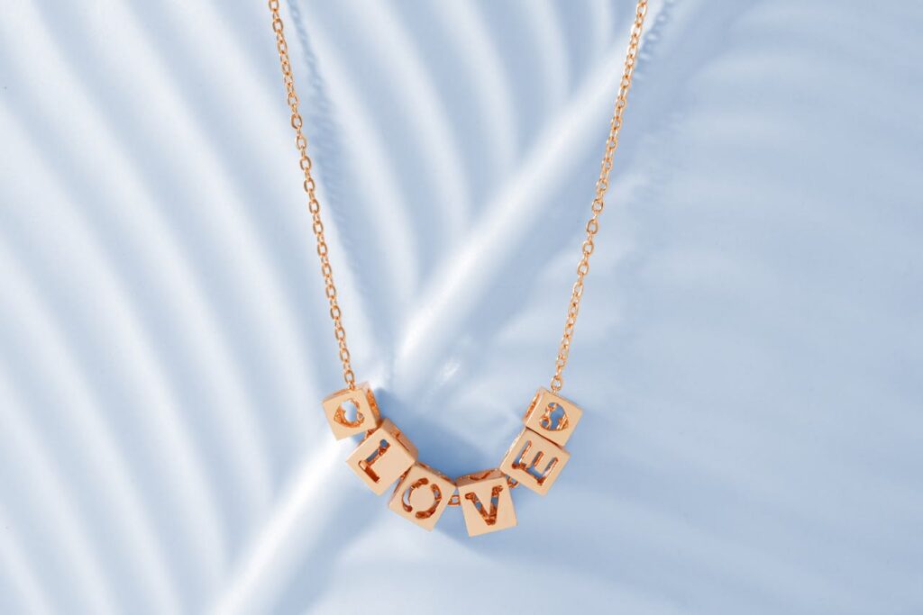 Elegant gold love pendant necklace with minimalist design on a white background.